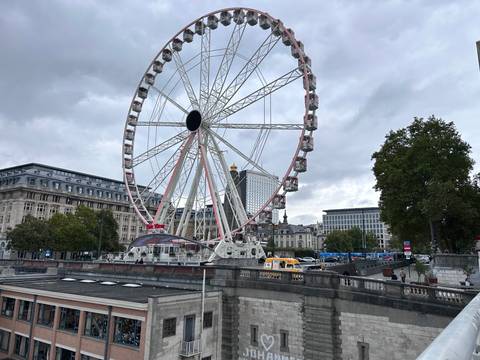 Ferris wheel in a cityscape with cloudy sky.