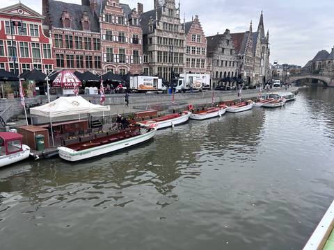 Boats lined up along a canal with historical buildings in the background.