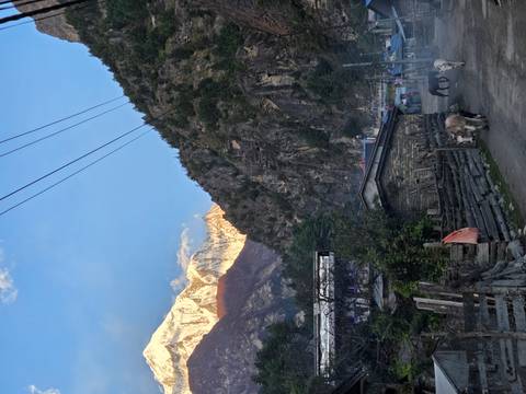 Village path surrounded by mountains at dawn with animals.