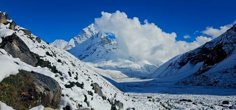 Snowy mountain landscape with clear blue sky and a valley.