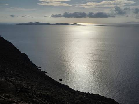 Calm sea reflecting the sun, seen from a cliff.