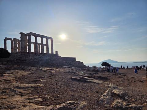 Group of tourists at ancient ruins with a sunny sky.