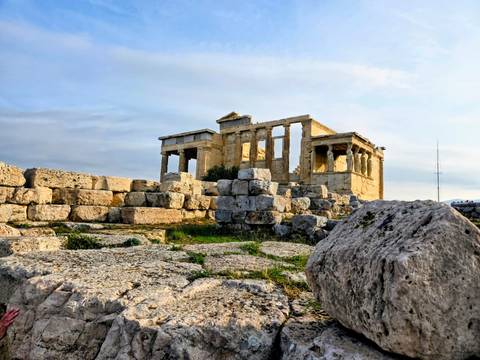 Ancient temple ruins on a hill under a clear sky.