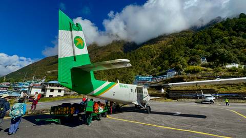 Small aircraft parked at an airport near mountains.