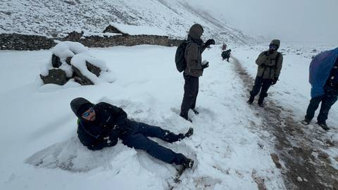 People playing in the snow on a mountainous path.