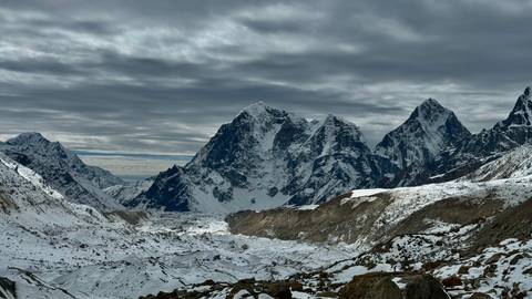 Snow-covered mountains under a cloudy sky.