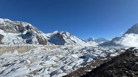 Wide view of a snow-covered landscape with mountains under a clear blue sky.