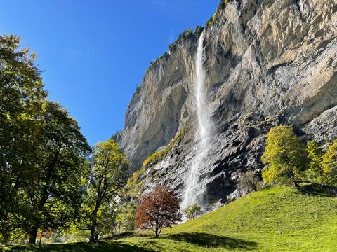 Waterfall cascading down a cliff in a green landscape.