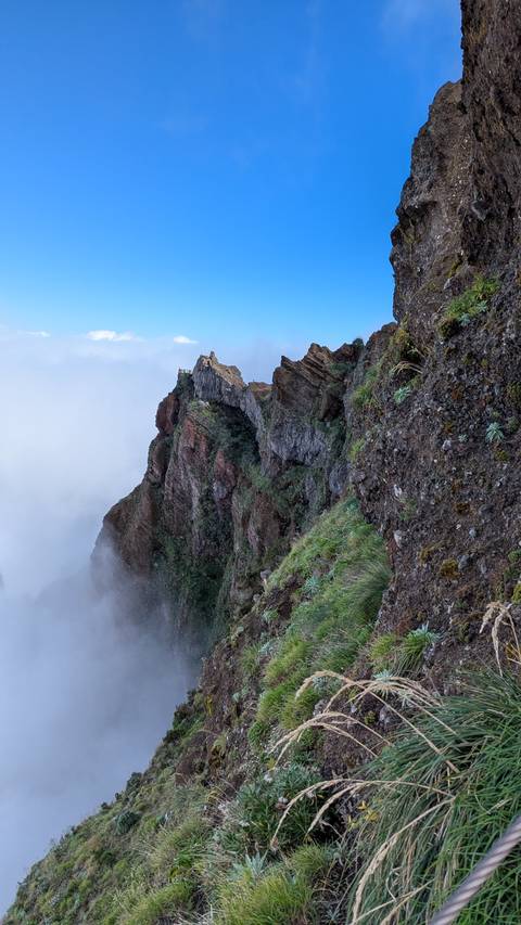 A scenic view of a rocky cliff with a small building on top, surrounded by mist.