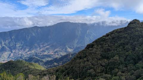 A vast mountainous landscape with a view of distant valleys and clouds.