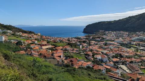A panoramic view of a coastal town with red-roofed buildings and the sea.