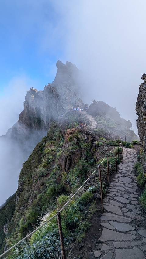 A cloudy mountain path with several hikers.