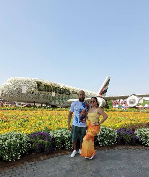 Two people standing in front of an aircraft covered in flowers.