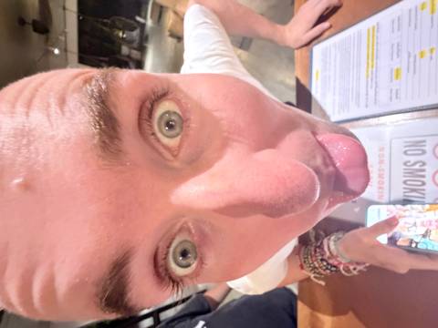 Close-up of a person making a face next to a menu