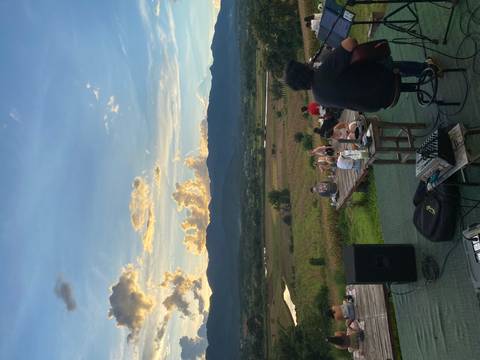 People sitting outside on decks facing a mountain view at sunset.