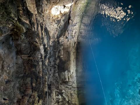 Underground cave filled with clear blue water.