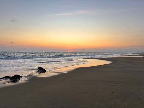 Beach at sunset with gentle waves.