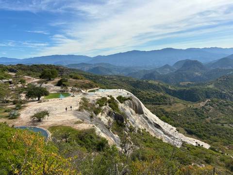 Scenic mountain view with natural pools and people walking nearby.