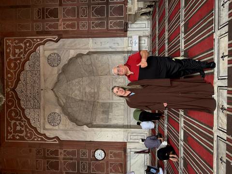 Two people posing inside a historic building with intricate carvings.