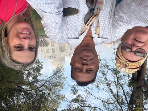 Three people taking a selfie with the Taj Mahal in the background.