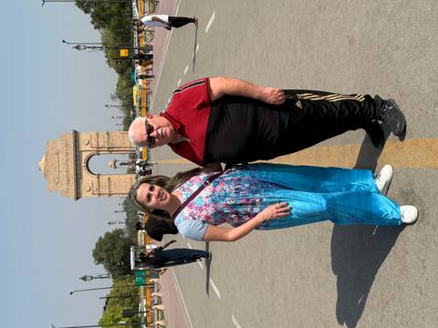 Two people standing in front of the India Gate.