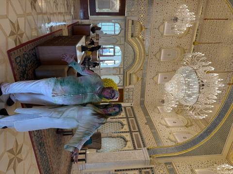 Two people covered in color pigment inside an ornate building.
