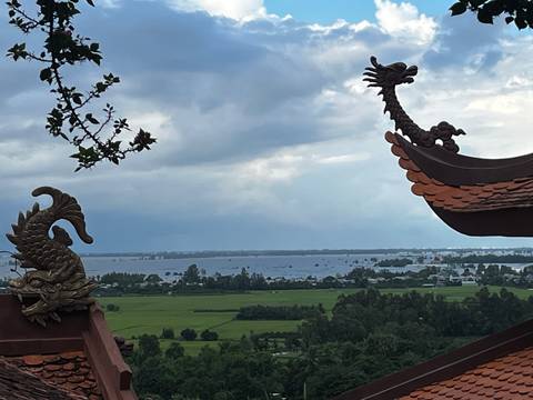 Decorative rooftop with dragon and sea creature sculptures overlooking a landscape.