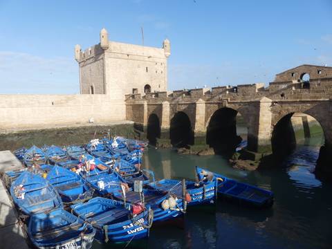 Boats docked by a stone bridge with historic architecture.