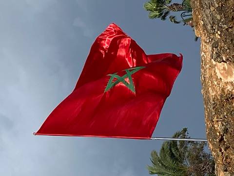 Moroccan flag waving against a cloudy sky.