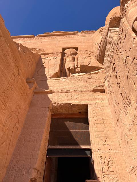 Intricate carvings and a towering statue at an Egyptian archaeological site.