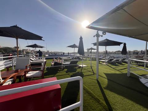 Sunny day on a cruise ship deck with loungers and umbrellas.