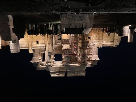 An ancient Egyptian temple illuminated at night with a crowd of visitors.
