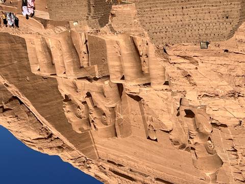 Massive ancient Egyptian statues at a famous archaeological site with visitors.