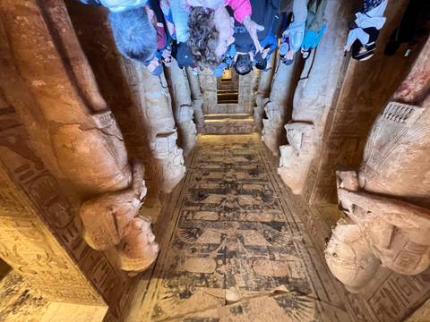 Visitors inside a grand hall with giant statues and intricate carvings.