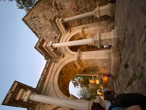 Ancient stone archway at dusk with people beneath.