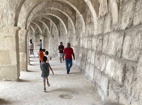 People walking through arched stone passageway.