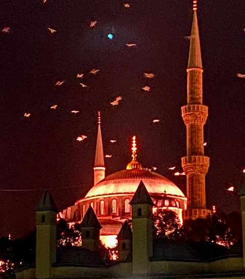 Mosque with illuminated dome and minarets at night.