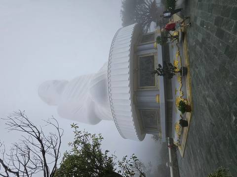 Large white statue of Buddha surrounded by fog.