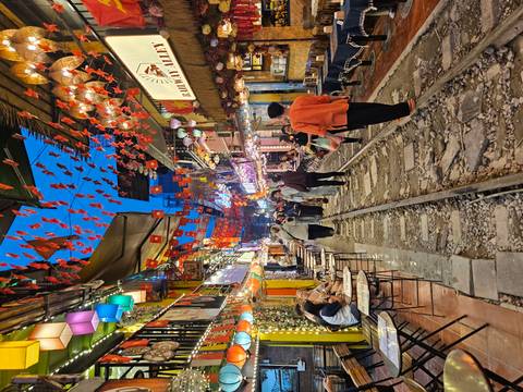 Vibrant street with railway track and tables.
