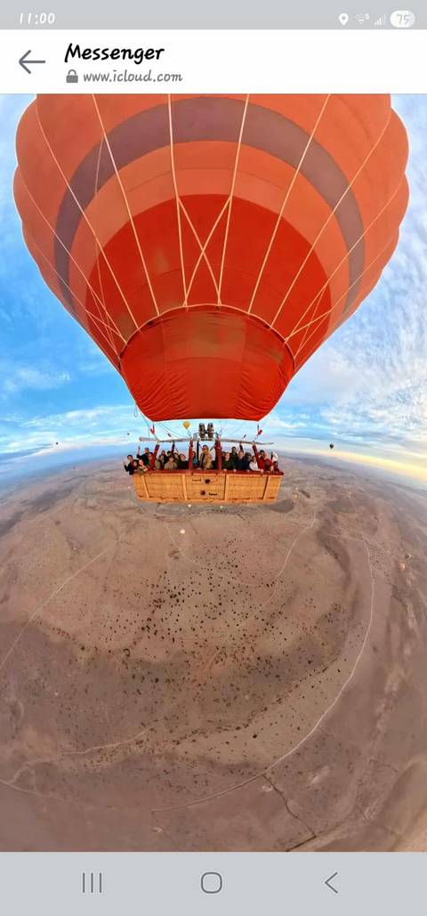 Hot air balloon carrying people over a desert landscape.