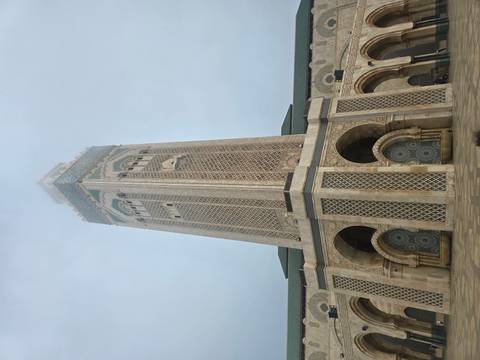 A grand mosque tower with intricate tile work under a clear sky.