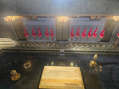 An ornate indoor space with flags and chandeliers reflecting on a shiny surface.