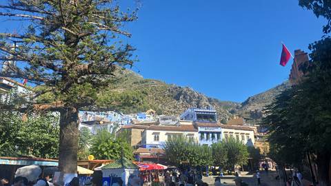 Street scene in Chefchaouen with mountain backdrop.