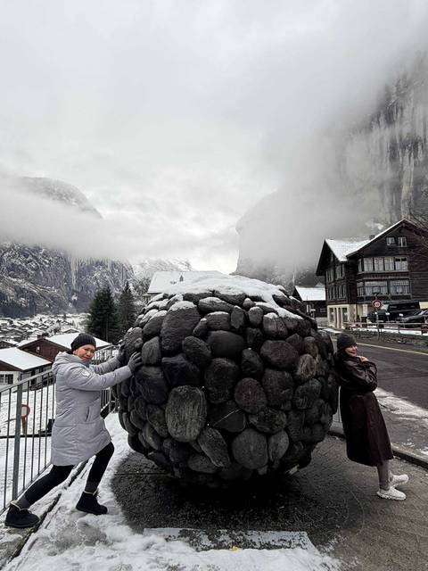 Two people posing with a large stone structure in the background.