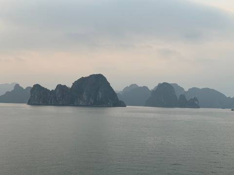 View of limestone islands in a calm bay with overcast skies.