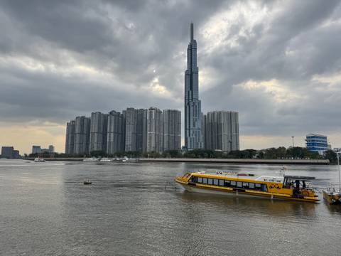 Cityscape with modern high-rise buildings and a river with boats.