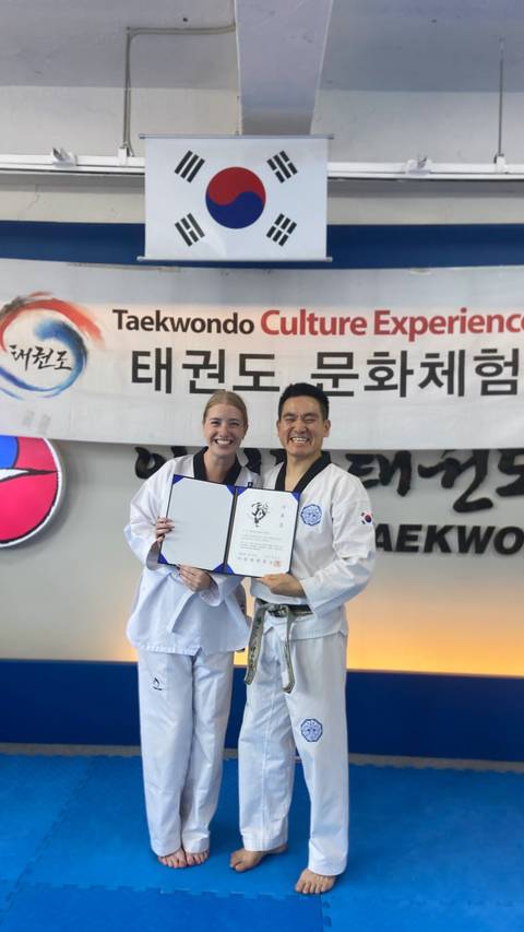 Two people posing with Taekwondo certificates.