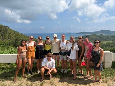 Group of people posing with a scenic backdrop of hills and sea.