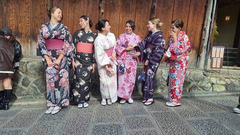 A group of people wearing traditional Japanese kimonos posing in front of a wooden wall.