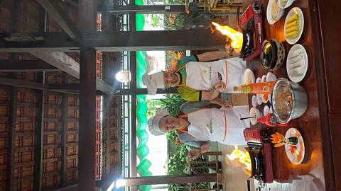 Two people in chef hats cooking at an outdoor station.